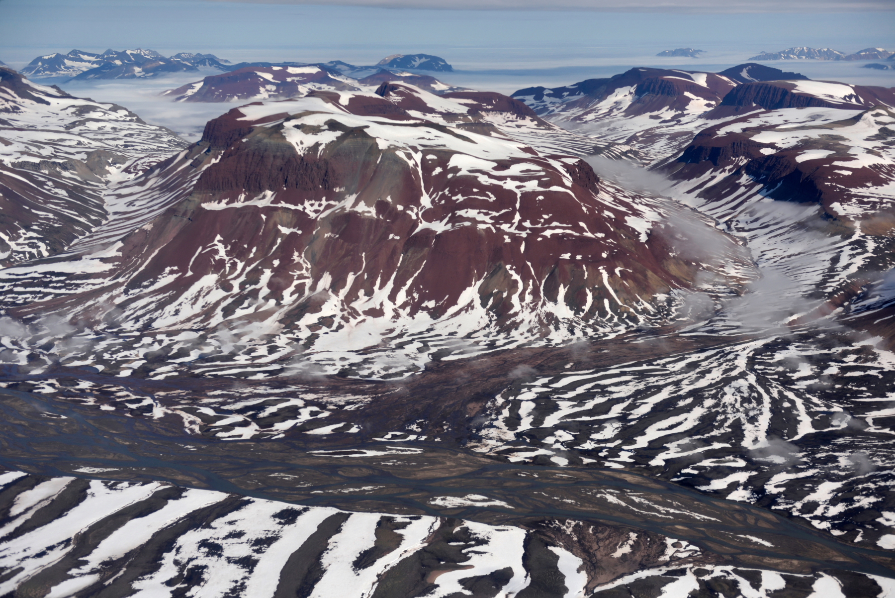 During our recent travels into the Arctic Circle, we were rewarded with many spectacular views from above of the Greenland landscape. This is one of our favourites. We just love the striking stripy pattern created by the colourful rocks and crisp white snow.